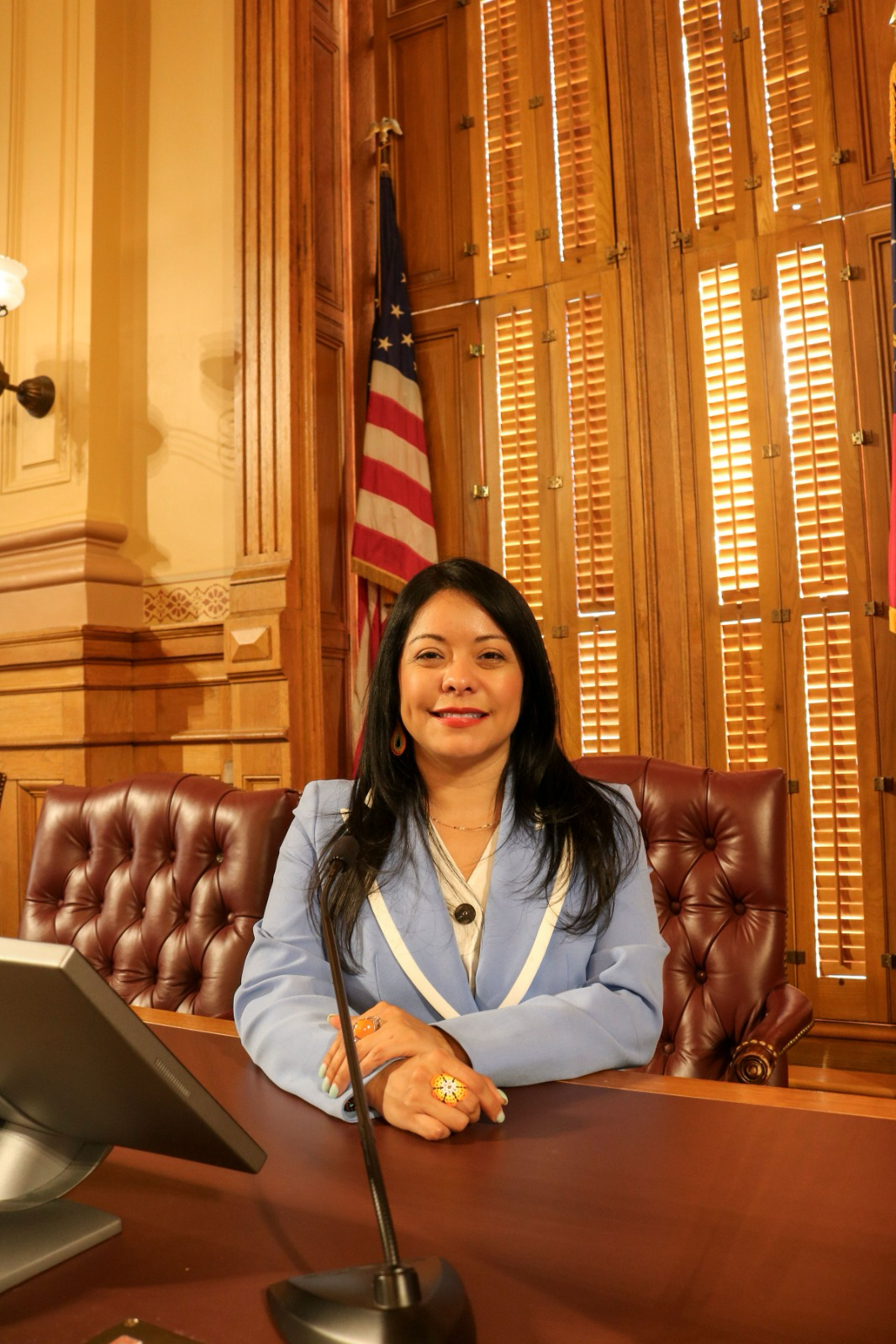 Brenda López Romero sentada en un escritorio del Capitolio de Georgia, con traje azul claro