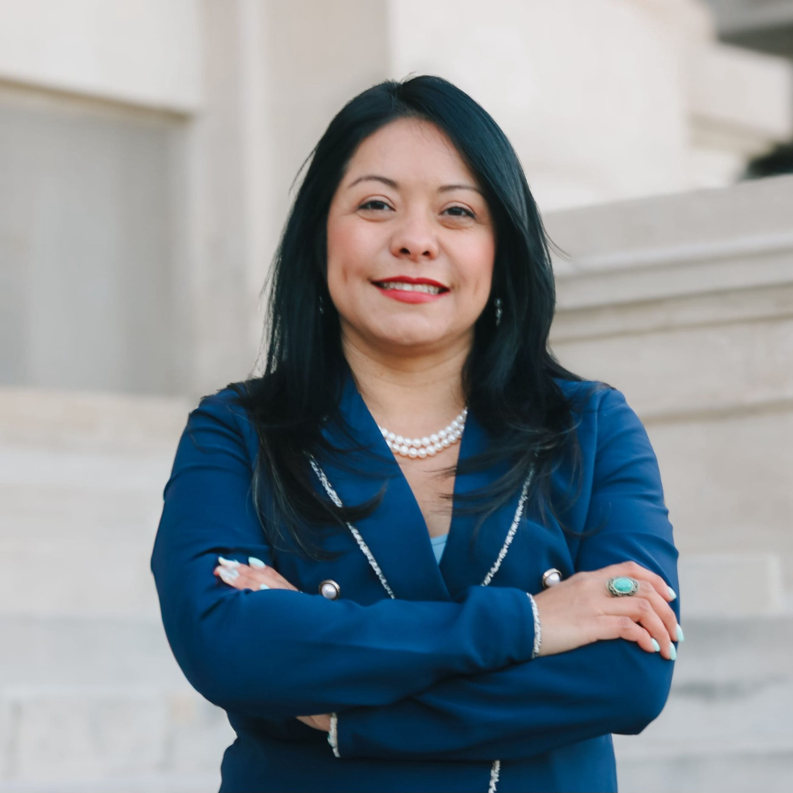 La Abogada Brenda López Romero con traje azul y los brazos cruzados